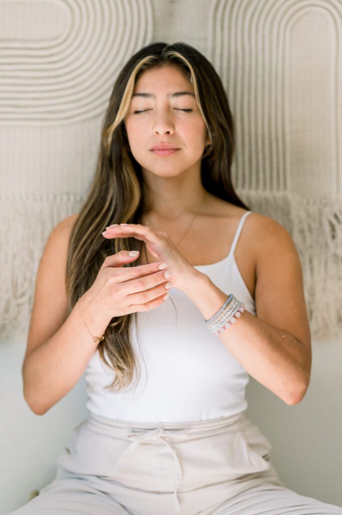 Woman self-administering tapping healing technique to hands.