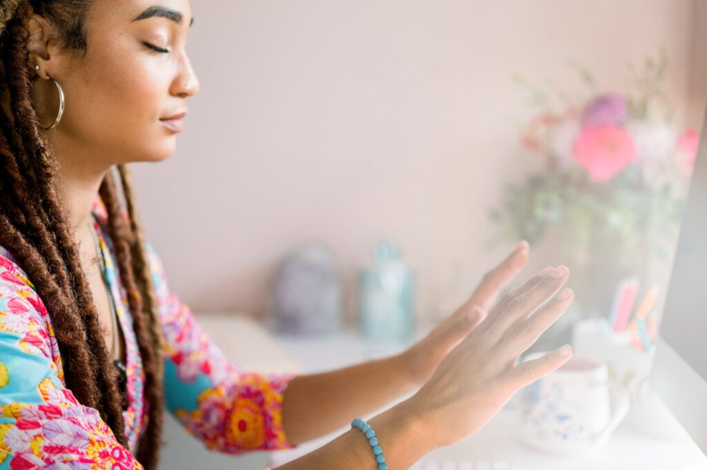 A healer with her hands held toward her computer in a distance healing session.