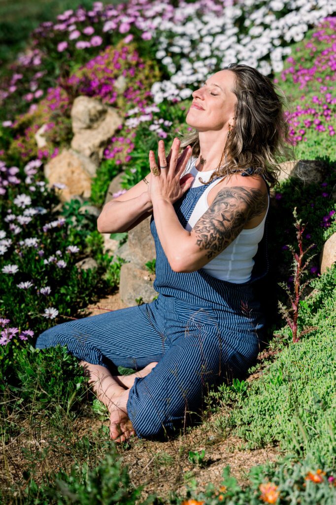 Joyous woman in meditation on hillside among flowers