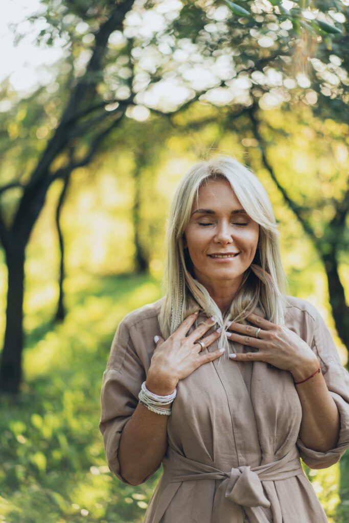 A person administering self-healing putting her hands over her heart.
