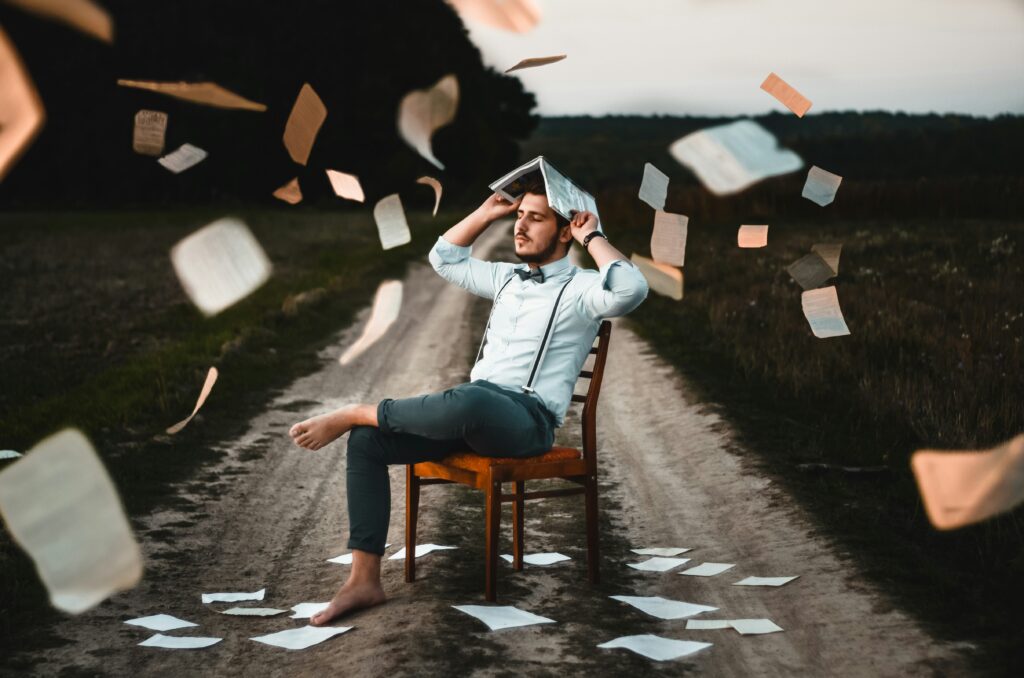 Man with book on head with pages falling around him