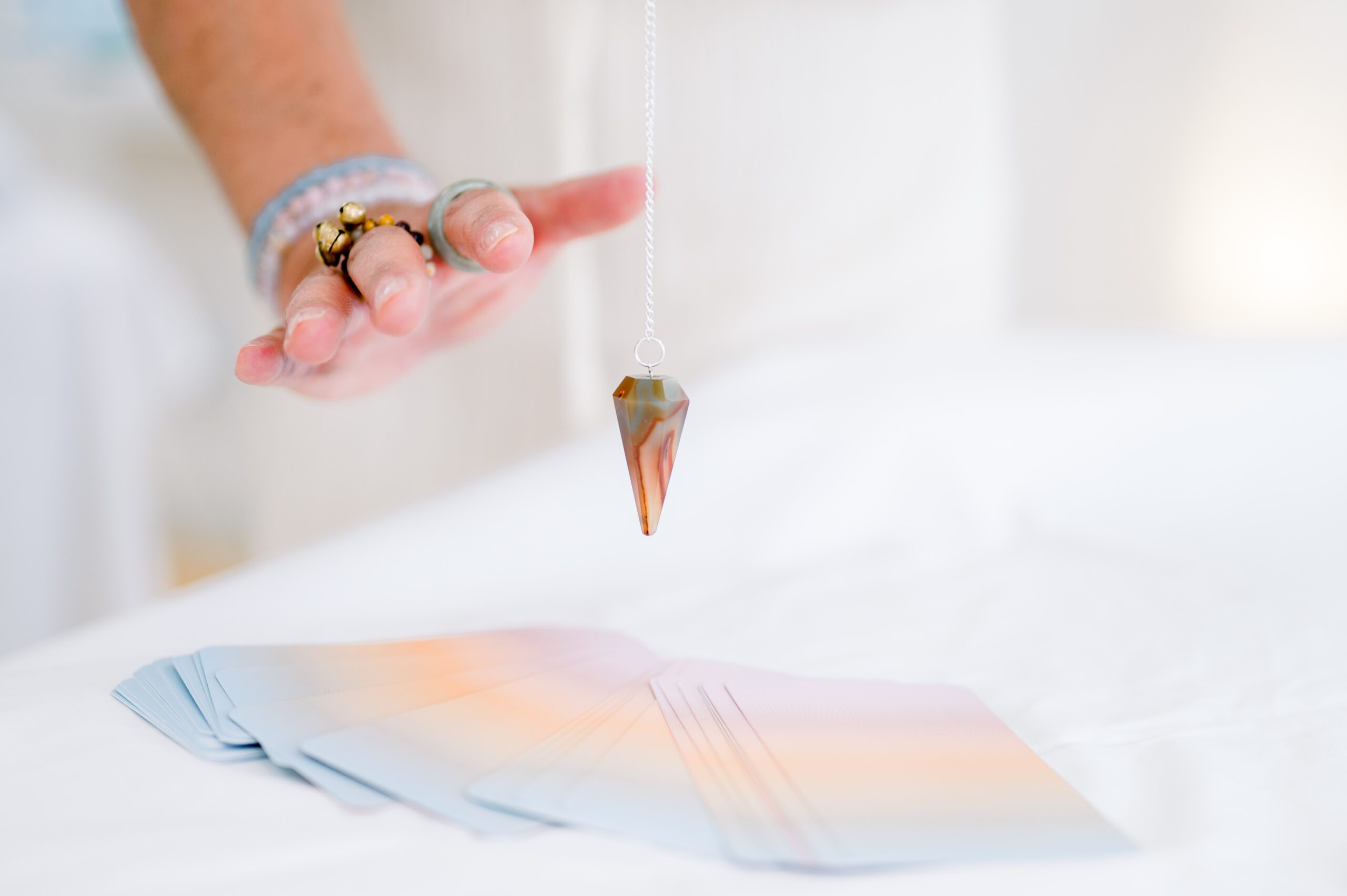 Woman holding pendulum over cards