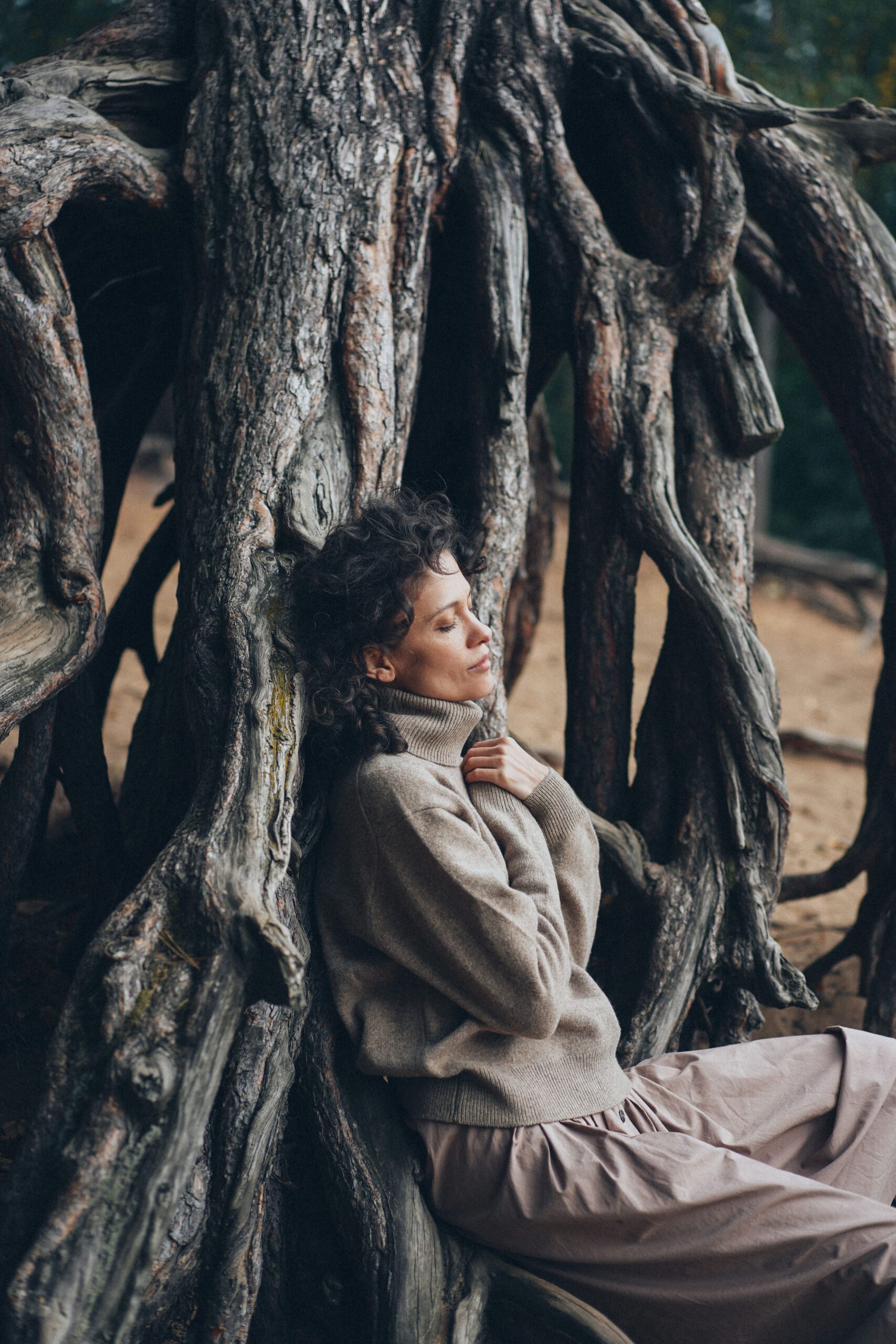 Woman sitting next to tree with hands on heart